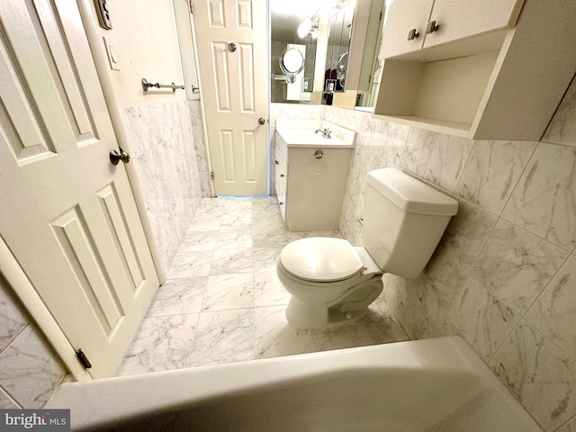 bathroom with toilet, vanity, and tile walls