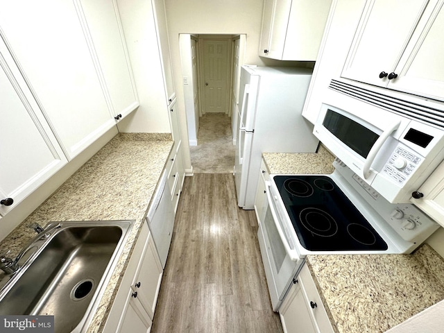 kitchen with white cabinets, light hardwood / wood-style floors, sink, and white appliances