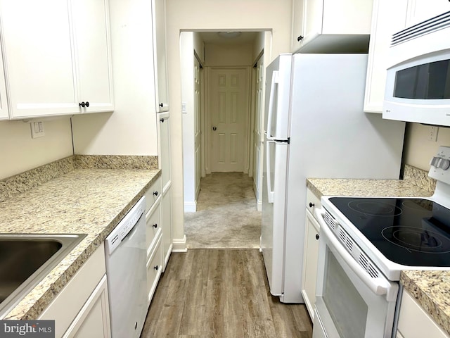 kitchen with white cabinets, light wood-type flooring, and white appliances