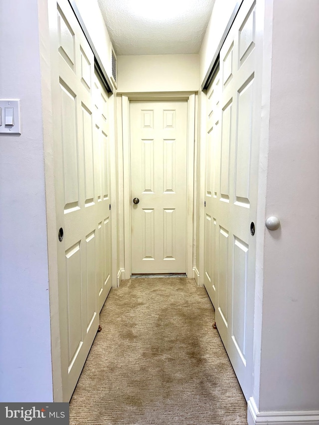 hallway with carpet and a textured ceiling