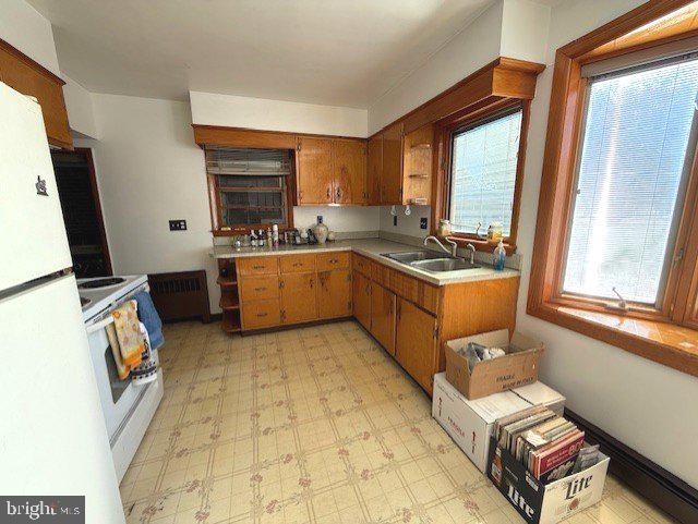 kitchen with a wealth of natural light, white appliances, and sink