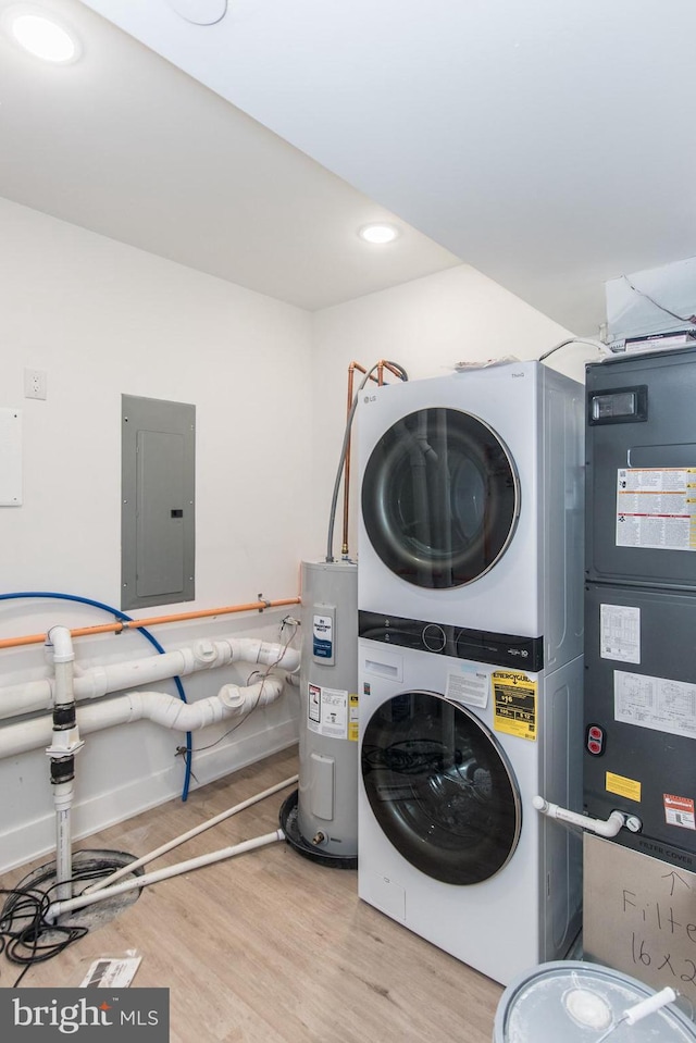 clothes washing area featuring water heater, stacked washing maching and dryer, electric panel, and light wood-type flooring