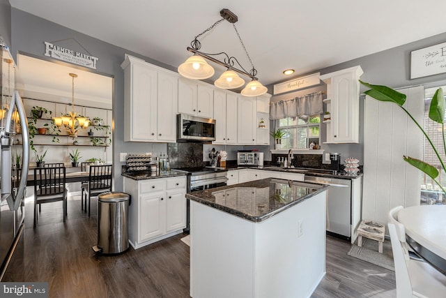 kitchen with a center island, white cabinetry, stainless steel appliances, and hanging light fixtures