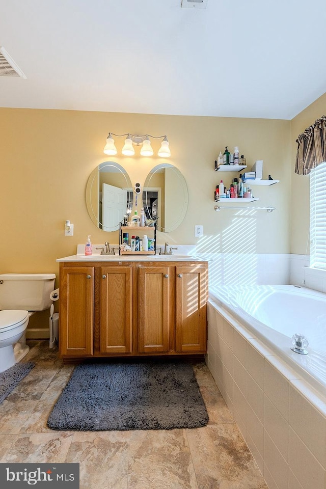 bathroom featuring a relaxing tiled tub, toilet, and vanity