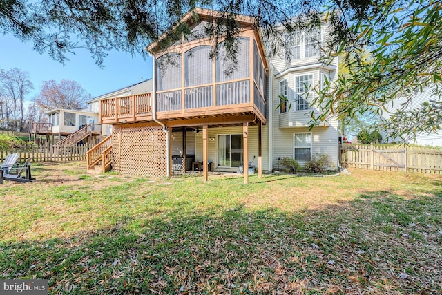 back of property featuring a wooden deck, a sunroom, and a yard