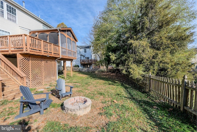 view of yard with a deck, an outdoor fire pit, and a sunroom