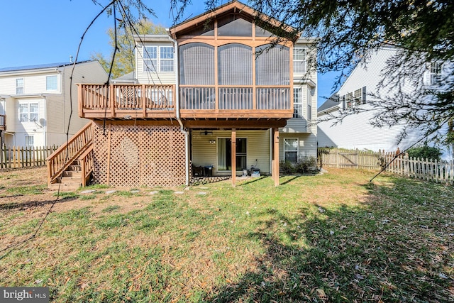 rear view of house featuring a sunroom, a wooden deck, and a lawn