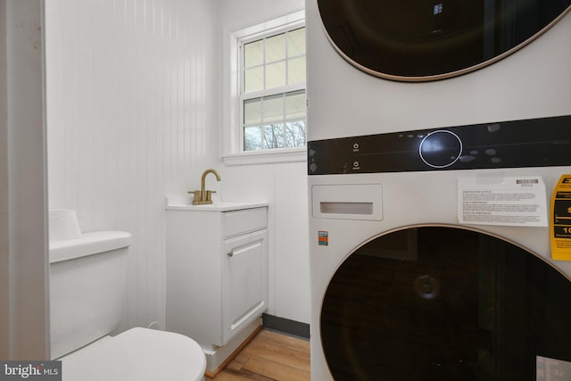 washroom with stacked washer and clothes dryer, sink, and light wood-type flooring