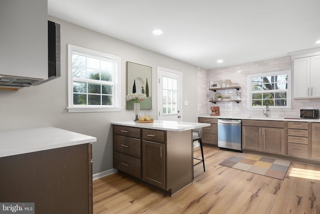 kitchen featuring stainless steel dishwasher, light hardwood / wood-style floors, sink, and a kitchen breakfast bar