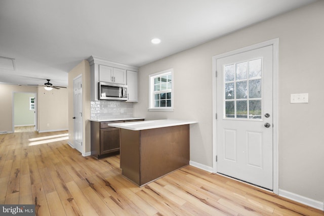 kitchen with ceiling fan, decorative backsplash, light wood-type flooring, and kitchen peninsula