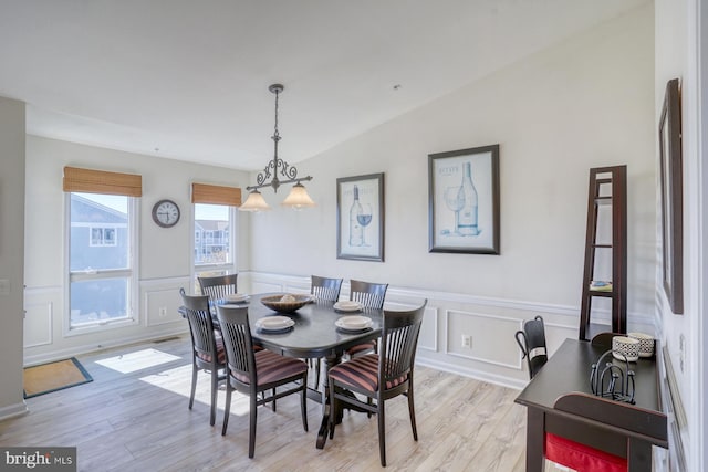 dining area with light wood-type flooring and vaulted ceiling