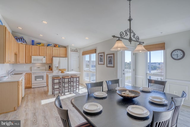 dining room with light hardwood / wood-style floors, lofted ceiling, and sink