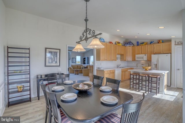 dining space featuring sink, light wood-type flooring, and lofted ceiling