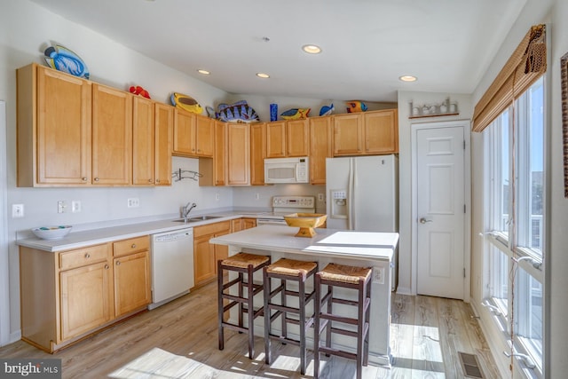 kitchen with light hardwood / wood-style floors, sink, white appliances, lofted ceiling, and a center island