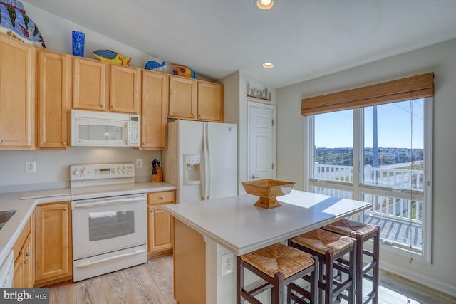 kitchen featuring white appliances, light hardwood / wood-style floors, a breakfast bar, and lofted ceiling