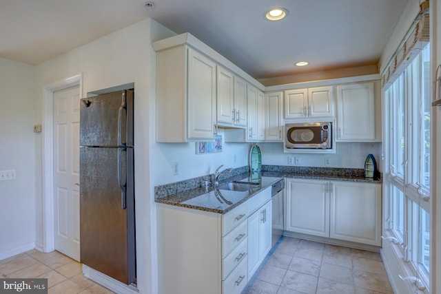 kitchen featuring stainless steel appliances, dark stone countertops, and white cabinets