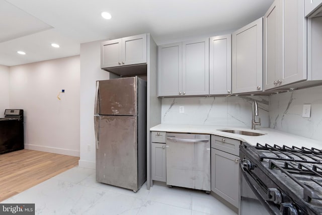 kitchen with decorative backsplash, stainless steel appliances, sink, light hardwood / wood-style flooring, and gray cabinets