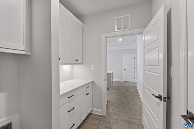 interior space with white cabinetry, crown molding, and light hardwood / wood-style flooring