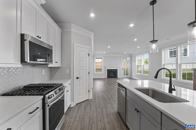 kitchen featuring light stone counters, crown molding, stainless steel appliances, dark hardwood / wood-style floors, and sink