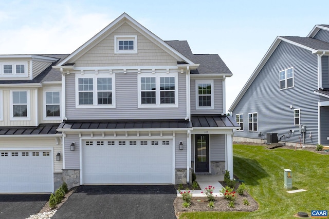 view of front of house with a garage, cooling unit, and a front lawn