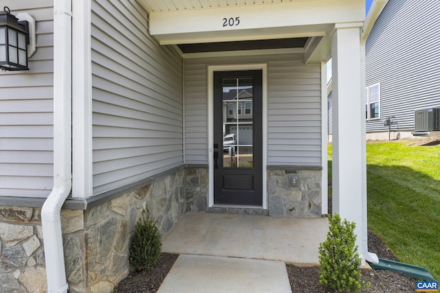 view of exterior entry with central air condition unit and a yard