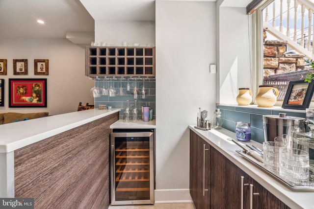 bar featuring dark brown cabinets, decorative backsplash, and beverage cooler