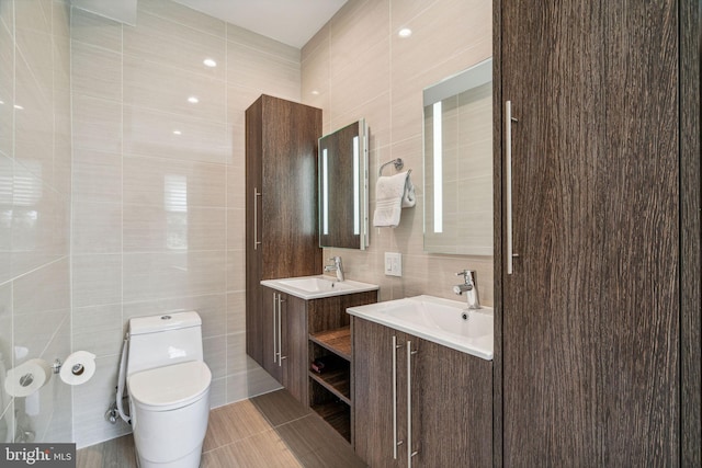 bathroom featuring toilet, vanity, tile walls, and tile patterned flooring