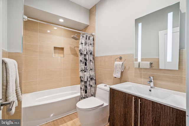 full bathroom with tile walls, vanity, toilet, and shower / tub combo