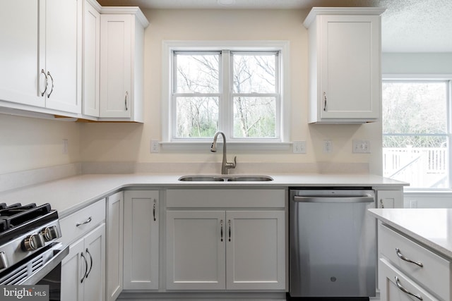 kitchen featuring white cabinets, appliances with stainless steel finishes, a textured ceiling, and sink