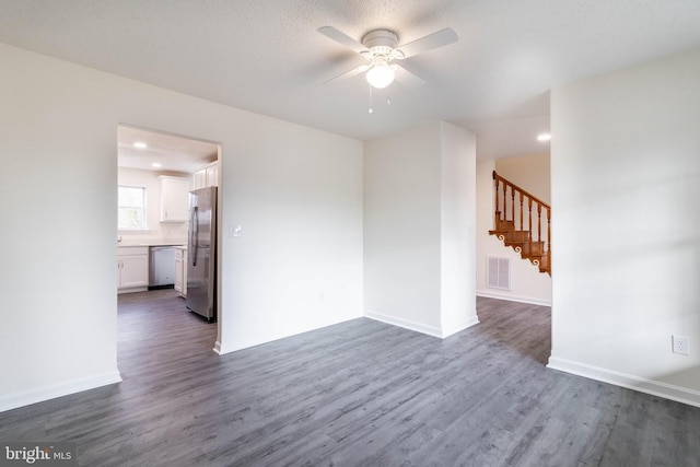 spare room with a textured ceiling, ceiling fan, and dark wood-type flooring