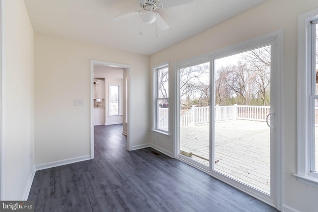 empty room with a textured ceiling, dark hardwood / wood-style flooring, and ceiling fan