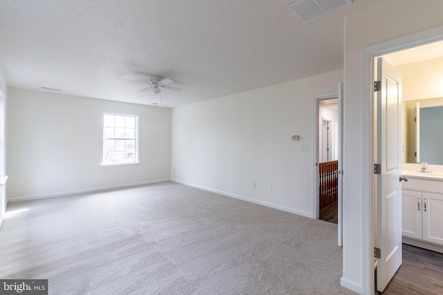 carpeted spare room with a textured ceiling, ceiling fan, and sink