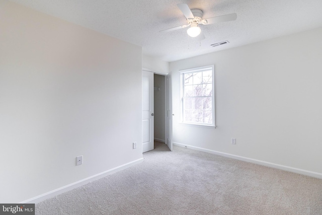 carpeted spare room featuring ceiling fan and a textured ceiling