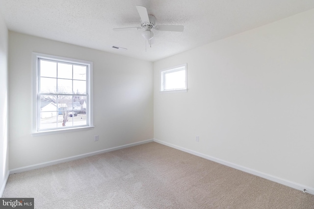 carpeted spare room with ceiling fan, a textured ceiling, and a wealth of natural light