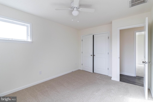 unfurnished bedroom with ceiling fan, light carpet, and a closet