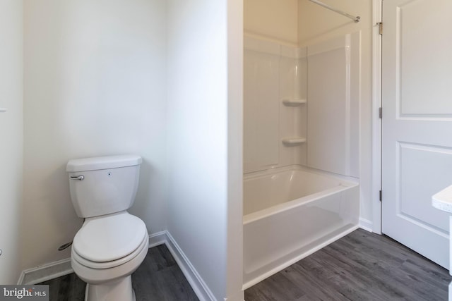 bathroom with hardwood / wood-style floors, toilet, and washtub / shower combination