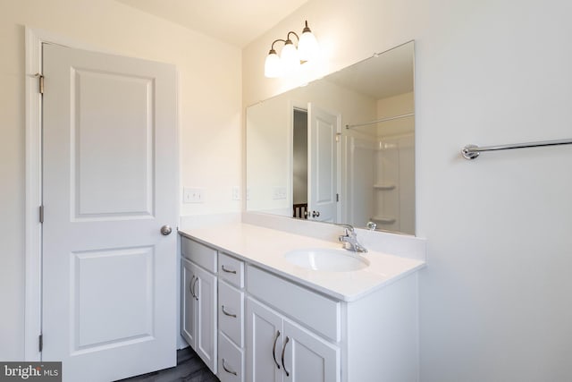 bathroom featuring hardwood / wood-style flooring, vanity, and walk in shower