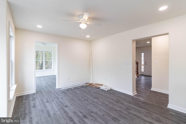 empty room with ceiling fan, dark wood-type flooring, and a textured ceiling