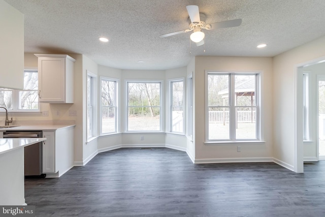 unfurnished dining area featuring ceiling fan, plenty of natural light, dark wood-type flooring, and a textured ceiling