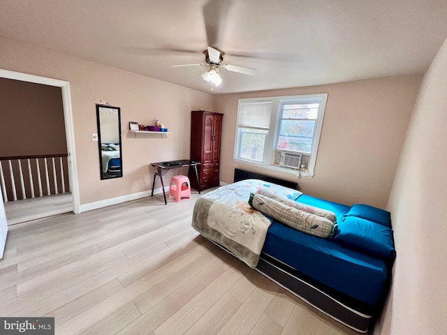 bedroom featuring light wood-type flooring, radiator heating unit, ceiling fan, and cooling unit