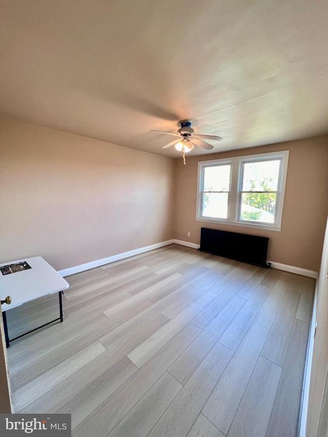 unfurnished room featuring light hardwood / wood-style floors, ceiling fan, and radiator