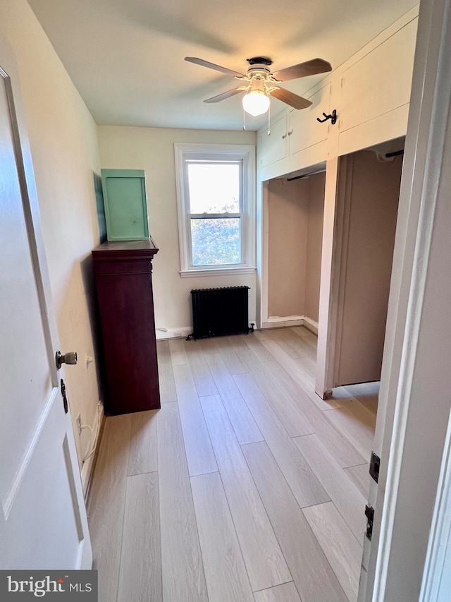 unfurnished bedroom featuring ceiling fan, radiator heating unit, and light hardwood / wood-style floors