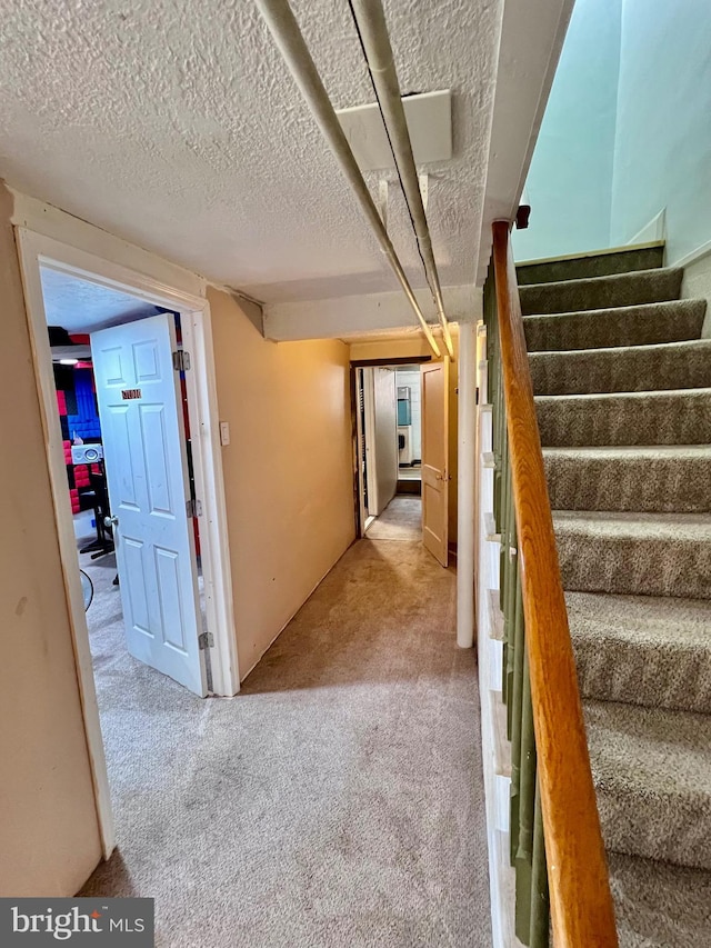 hall with light colored carpet and a textured ceiling