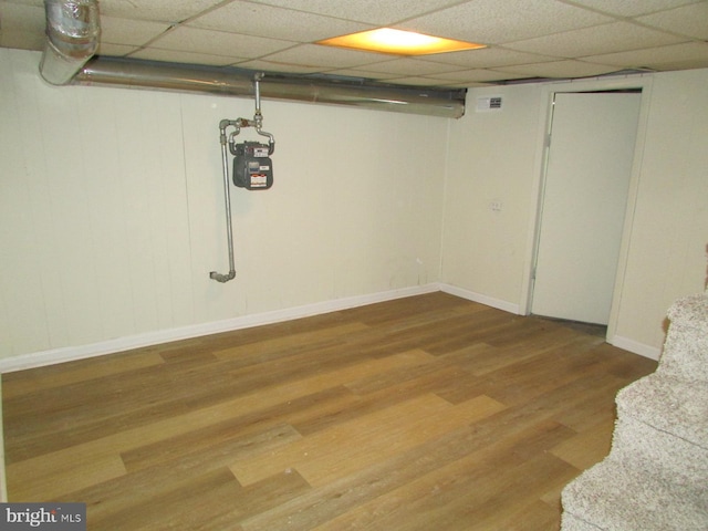 basement with light wood-type flooring and a paneled ceiling