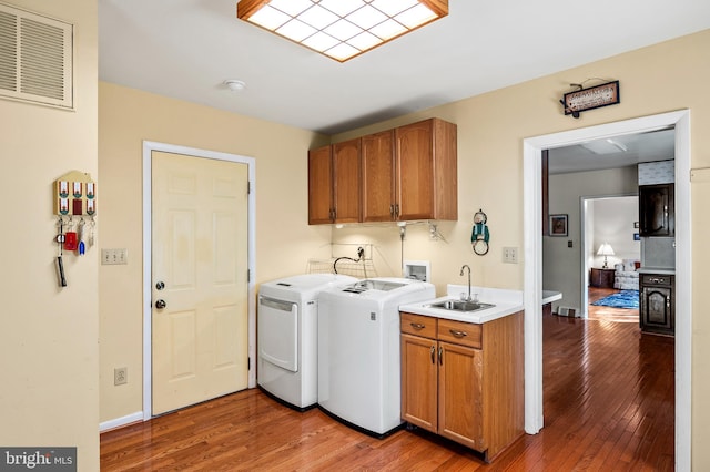 laundry area featuring cabinets, washer and dryer, sink, and hardwood / wood-style floors