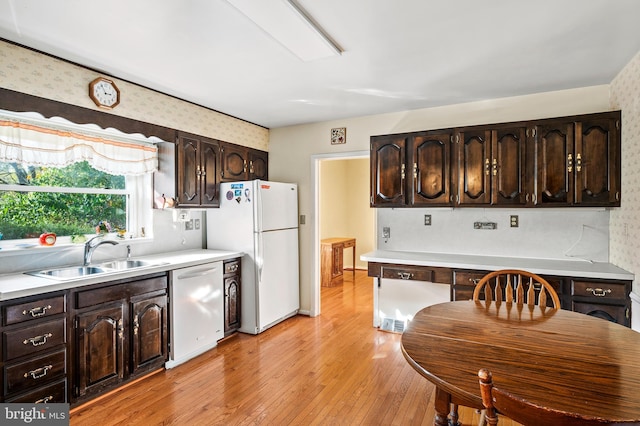 kitchen with white appliances, dark brown cabinets, sink, and light wood-type flooring