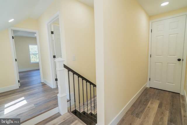 corridor with hardwood / wood-style floors and vaulted ceiling