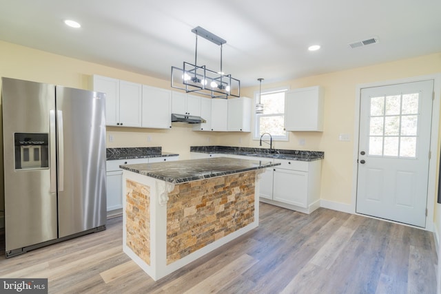 kitchen with white cabinets, a kitchen island, and stainless steel fridge