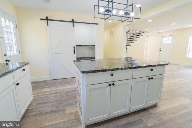 kitchen with decorative light fixtures, white cabinetry, a barn door, and a healthy amount of sunlight