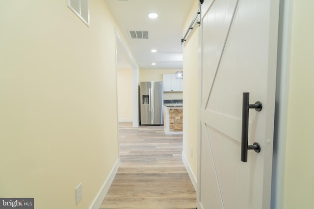 hall featuring light hardwood / wood-style floors and a barn door